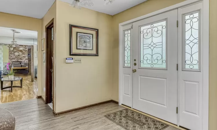 Foyer entrance featuring plenty of natural light, light hardwood / wood-style floors, and an inviting chandelier