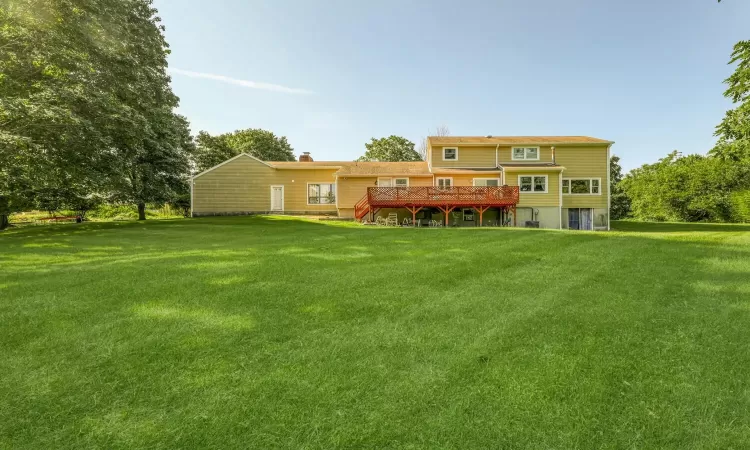 Rear view of property with a deck and a yard