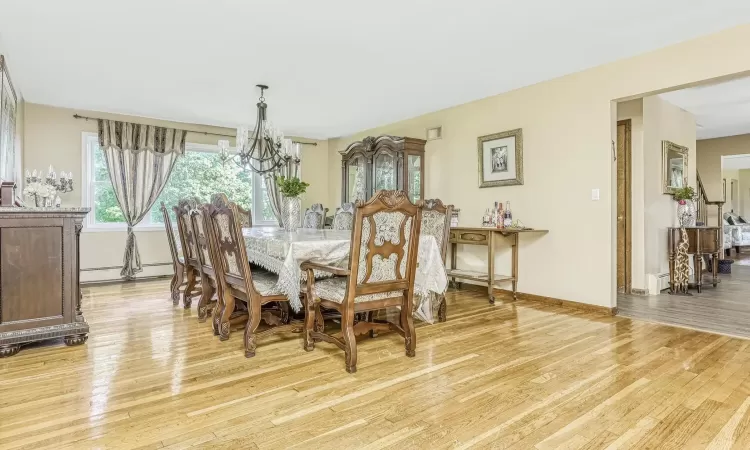 Dining space with light hardwood / wood-style floors, baseboard heating, and a chandelier