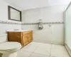 Bathroom with vanity, tile patterned flooring, toilet, tile walls, and a shower with shower door