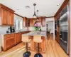 Kitchen featuring appliances with stainless steel finishes, ornamental molding, light hardwood / wood-style floors, a kitchen island, and hanging light fixtures