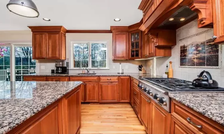 Kitchen with stainless steel gas stovetop, light stone counters, plenty of natural light, and light hardwood / wood-style flooring