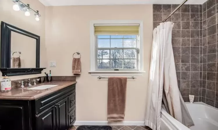 Bathroom featuring tile patterned floors, vanity, and shower / bathtub combination with curtain