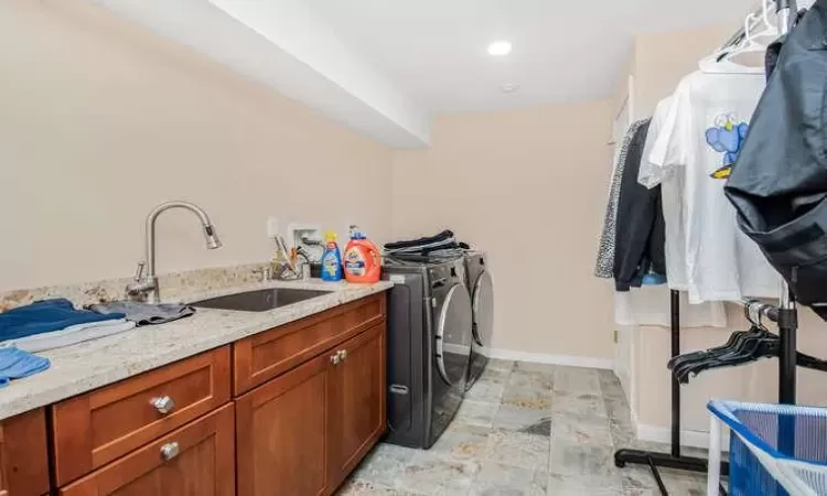 Washroom with cabinets, independent washer and dryer, and sink