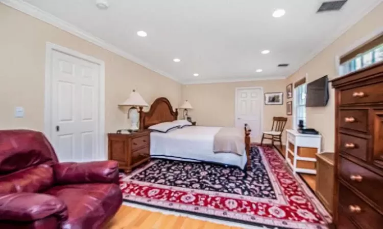 Bedroom with hardwood / wood-style flooring and ornamental molding