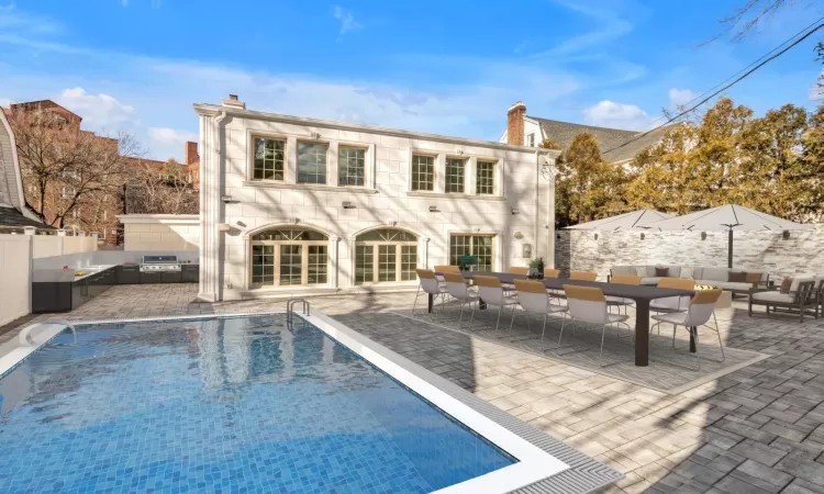 Rear view of property with a fenced in pool and a patio area