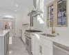 Kitchen with sink, wall chimney range hood, appliances with stainless steel finishes, white cabinets, and ornamental molding (STAGED)