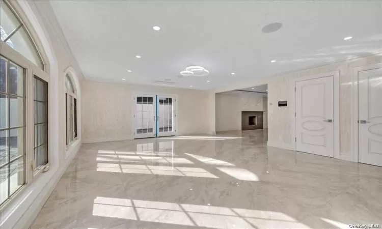 Unfurnished living room featuring a fireplace, plenty of natural light, and ornamental molding