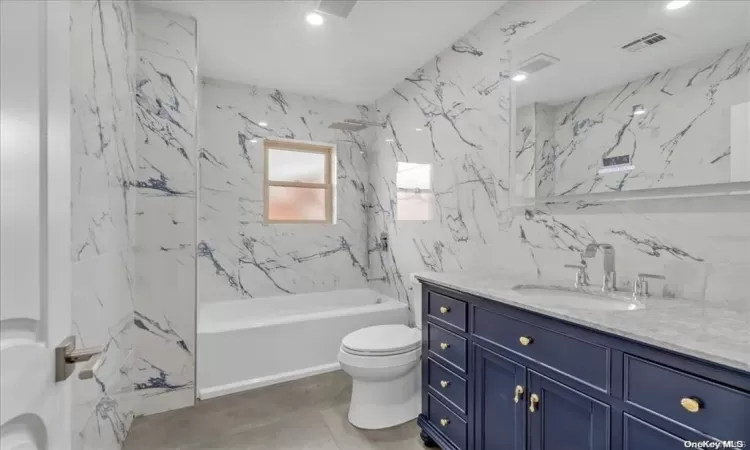 Full bathroom featuring vanity, toilet, and tiled shower / bath