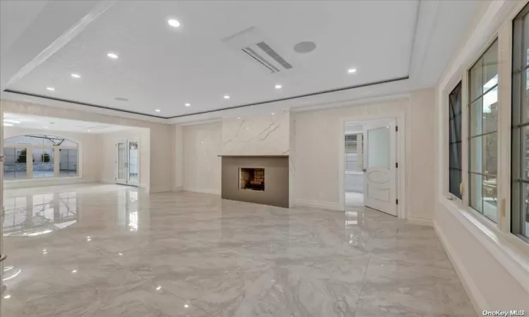 Unfurnished living room featuring plenty of natural light, crown molding, and a high end fireplace