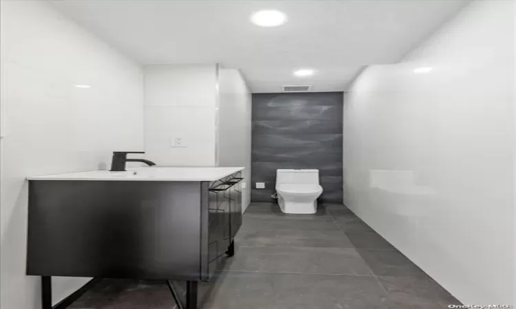 Bathroom with vanity, tile walls, and toilet