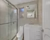 Bathroom with vanity, a shower with shower door, tile walls, and toilet