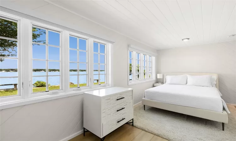 Bedroom with light hardwood / wood-style flooring and a water view