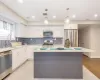 Kitchen featuring decorative light fixtures, a center island, stainless steel appliances, and white cabinetry