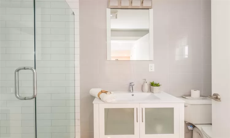 Bathroom featuring vanity, toilet, and a shower with shower door