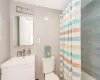 Full bathroom with shower / bath combo with shower curtain, vanity, tile walls, and toilet