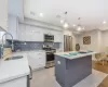 Kitchen featuring sink, decorative light fixtures, a kitchen island, white cabinetry, and stainless steel appliances