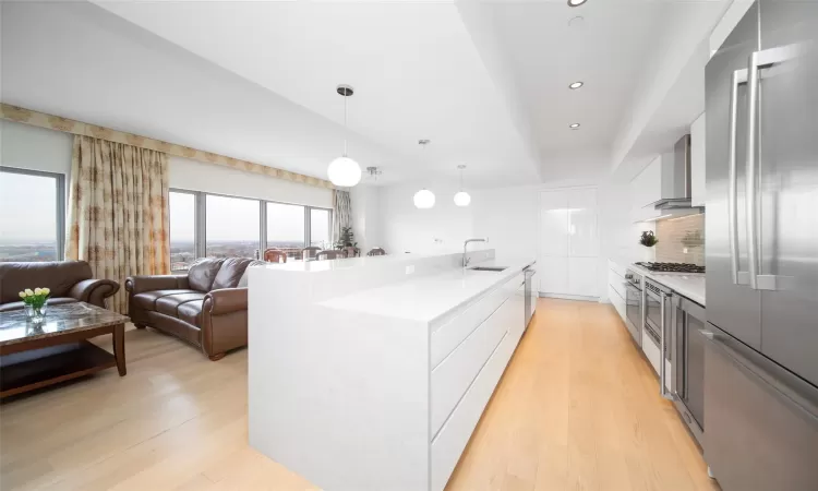 Kitchen featuring sink, light hardwood / wood-style flooring, decorative backsplash, hanging light fixtures, and appliances with stainless steel finishes