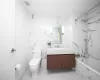 Full bathroom with tile walls, toilet, vanity, and tiled shower / bath