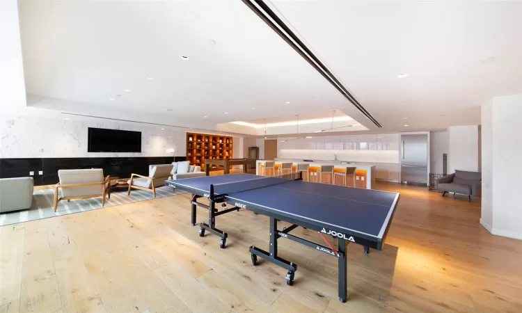 Recreation room with light hardwood / wood-style floors and a tray ceiling