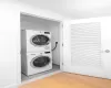 Laundry area with stacked washer and clothes dryer and hardwood / wood-style floors