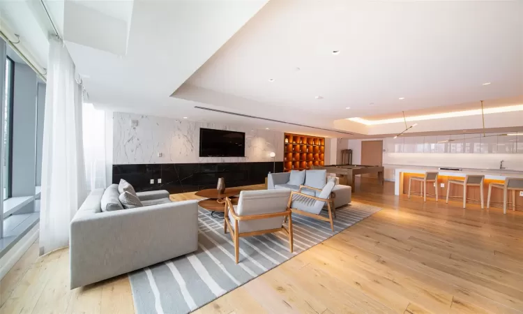 Living room with a tray ceiling and light hardwood / wood-style flooring