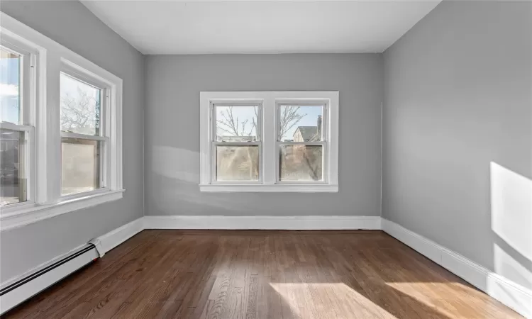 Unfurnished room with a baseboard radiator and dark hardwood / wood-style flooring