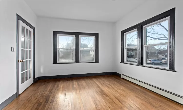 Empty room with baseboard heating, french doors, and hardwood / wood-style flooring