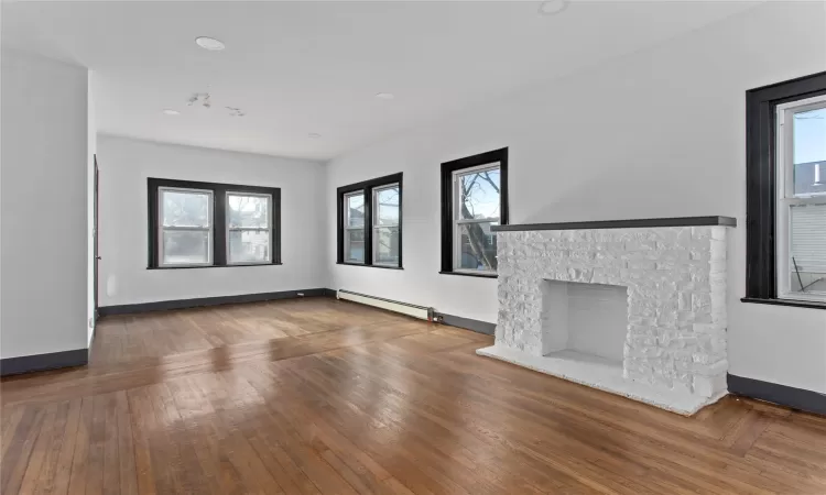 Unfurnished living room featuring a baseboard radiator, a fireplace, and dark hardwood / wood-style floors