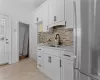 Kitchen with white cabinets, stainless steel fridge, tasteful backsplash, and sink