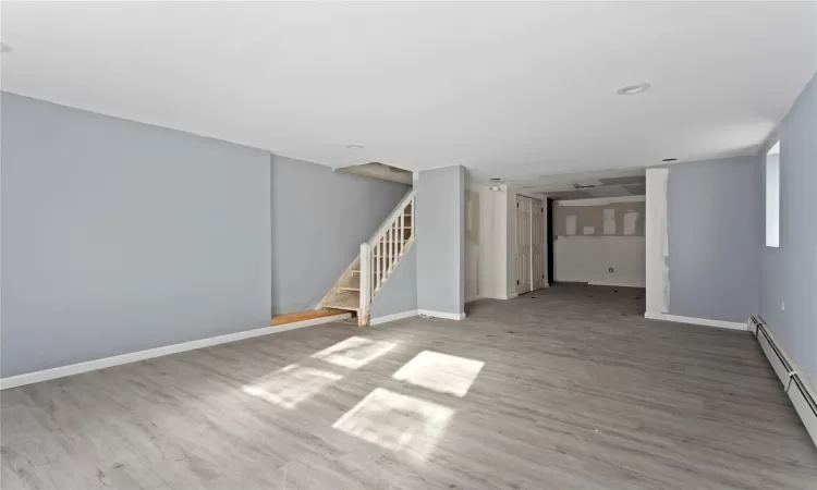 Unfurnished room featuring a baseboard radiator and hardwood / wood-style floors