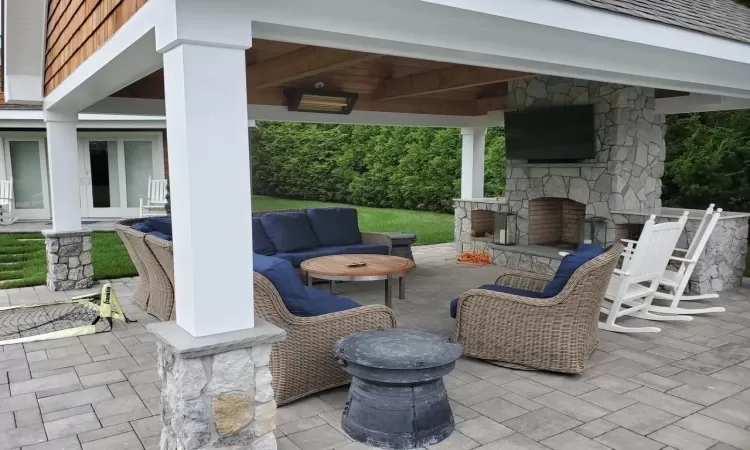 Back of property featuring a lawn, a patio area, a gazebo, and an outdoor living space with a fireplace