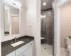 Bathroom featuring walk in shower, tile patterned flooring, vanity, and toilet