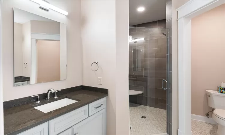 Bathroom featuring walk in shower, tile patterned flooring, vanity, and toilet