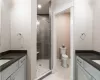 Bathroom with vanity, tile patterned flooring, toilet, and a shower with shower door