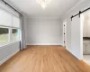 Spare room with ornamental molding, a barn door, and light hardwood / wood-style flooring