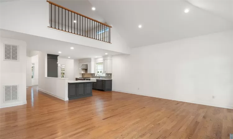 Unfurnished living room featuring high vaulted ceiling and light hardwood / wood-style flooring