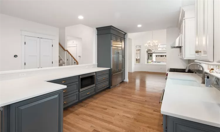 Kitchen featuring a notable chandelier, built in microwave, gray cabinetry, and white cabinetry