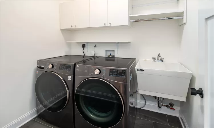 Laundry room featuring cabinets, separate washer and dryer, dark tile patterned flooring, and sink