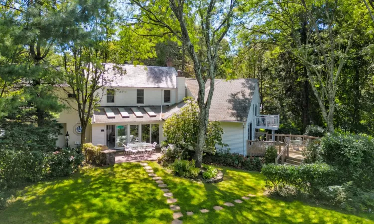 Rear view of house with a deck, a patio area, and a lawn