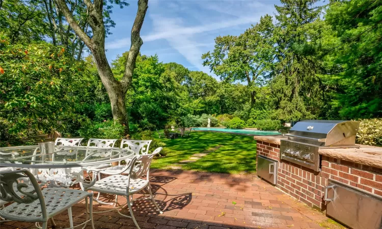 View of patio featuring a grill, a swimming pool, and exterior kitchen