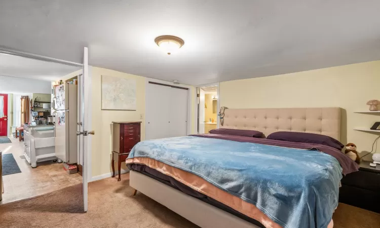 Bedroom featuring connected bathroom, light carpet, and a closet