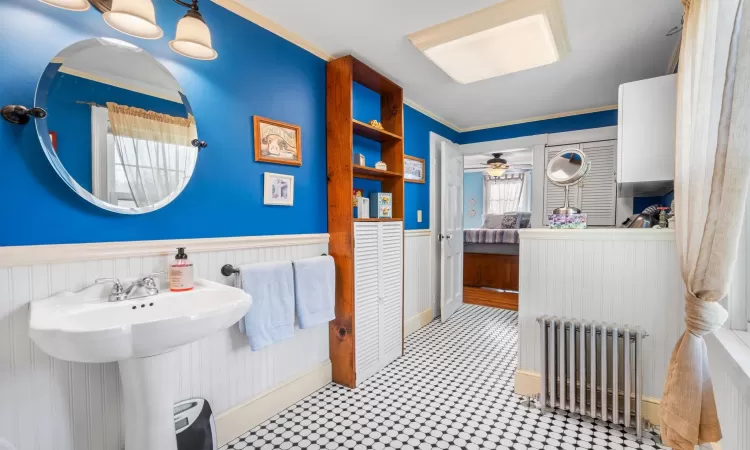 Bathroom with ceiling fan, sink, crown molding, and radiator