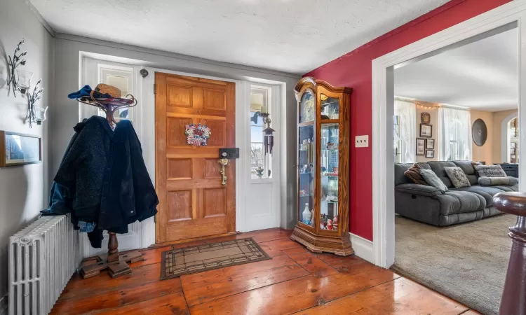 Carpeted entryway with a textured ceiling and radiator