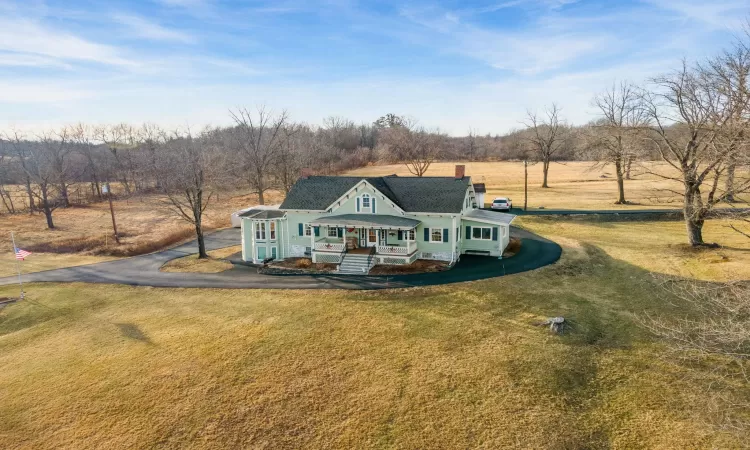 View of front of home featuring a rural view, covered porch, and a front lawn