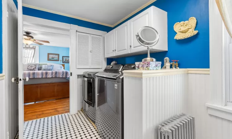 Clothes washing area featuring cabinets, radiator, ornamental molding, ceiling fan, and separate washer and dryer