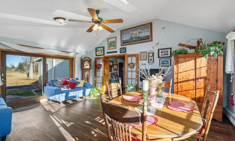 Dining space with baseboard heating, ceiling fan, and lofted ceiling with skylight