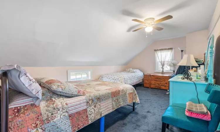 Carpeted bedroom with ceiling fan and lofted ceiling