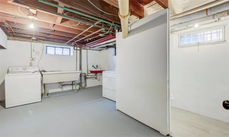 Basement with washer and clothes dryer, sink, and a wealth of natural light