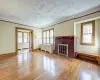 Unfurnished living room featuring hardwood / wood-style floors, crown molding, radiator, and a brick fireplace